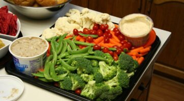 veggie tray with broccoli, carrots, cauliflower, tomatoes, snap peas, and ranch dips