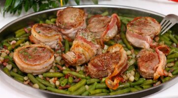 picture of bacon wrapped pork chops on a bed of green beans