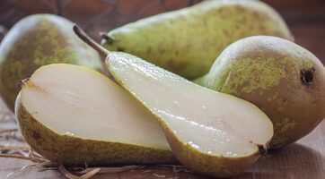 closeup of pears and a pear cut in half with a brown background