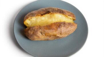 close up of baked potato cut in half on blue plate with white background